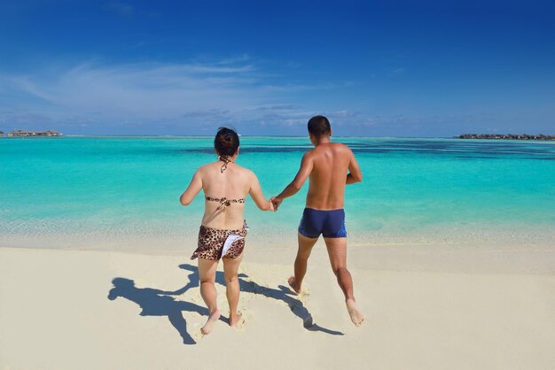 Um jovem casal asiático feliz se diverte e passa um tempo romântico no verão em uma bela praia de areia branca.