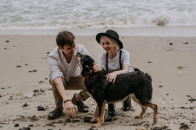 Um jovem casal atraente a divertir-se na praia com um cão.