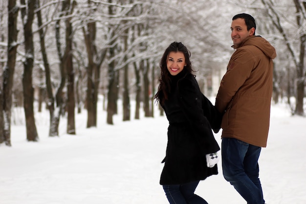 Um jovem casal caminha em um parque de inverno ao ar livre