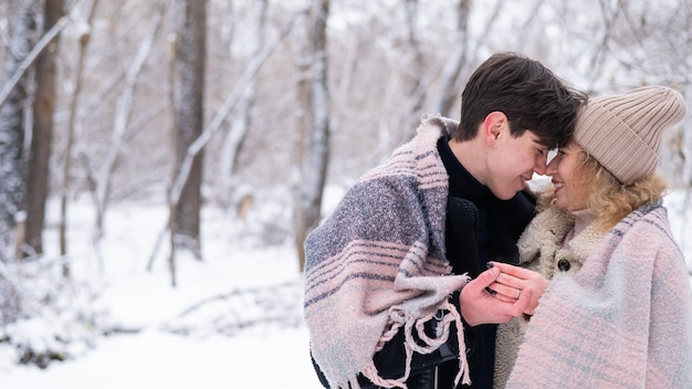 Um jovem casal caminha no parque no inverno, o cara e a garota estão bebendo uma bebida quente ao ar livre