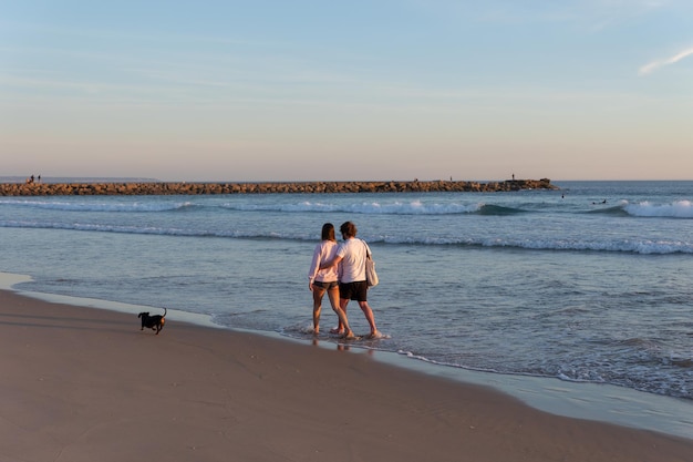 Um jovem casal caminhando à beira-mar