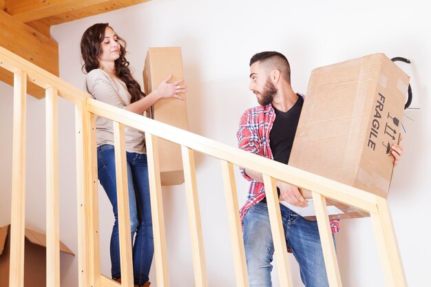 Foto um jovem casal carregando as caixas na casa nova.