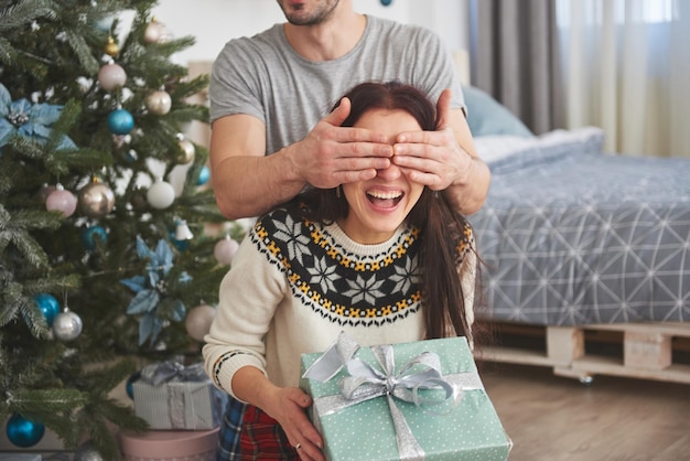 Um jovem casal comemorando o natal um homem de repente apresentou um presente para sua esposa o conceito de felicidade familiar e bem-estar