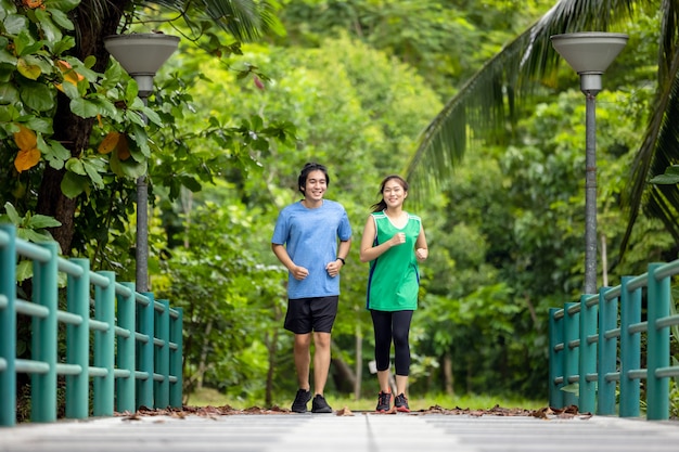 Um jovem casal correndo no parque, Esporte e amor se combinam neste conceito, com um homem e uma mulher esportivos fazendo exercícios juntos.