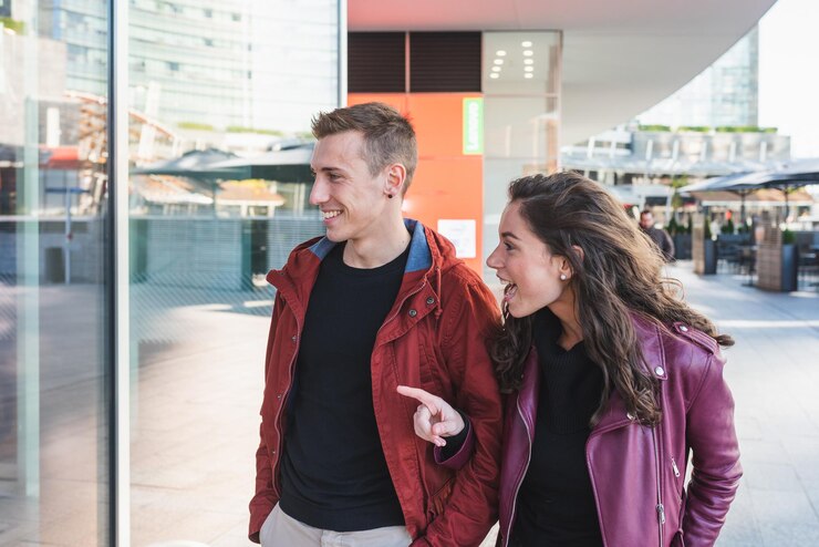 Foto um jovem casal da moda anda pela cidade para fazer compras, ela fica impressionada com o que vê na vitrine conceito de amor às compras de natal