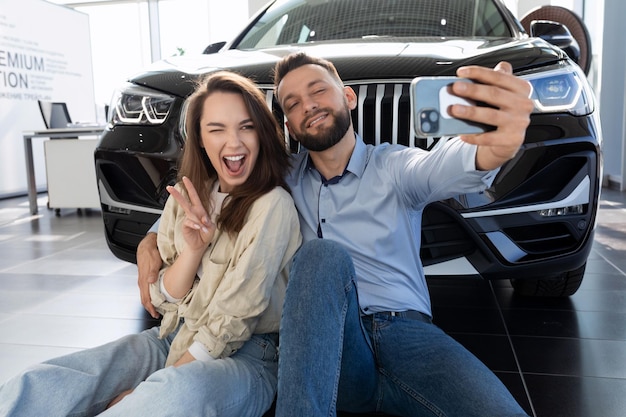 Foto um jovem casal de família feliz é fotografado ao lado de um novo suv comprado em uma concessionária de carros