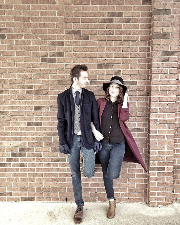 Foto um jovem casal de moda apoiado numa parede de tijolos na cidade.