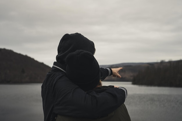 Um jovem casal de pé em frente a um lago
