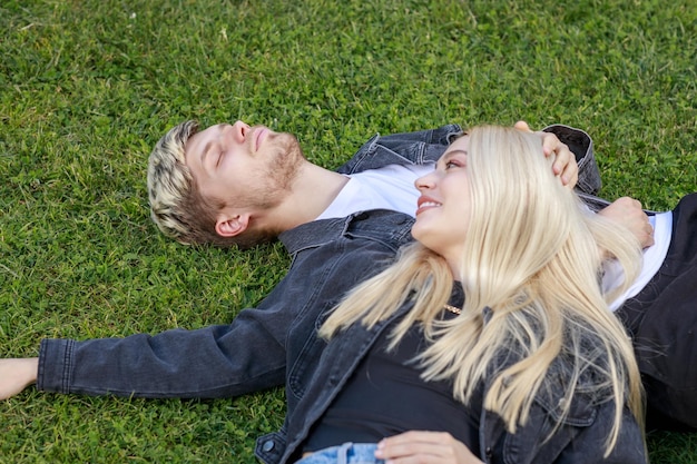 Um jovem casal deitado na grama e sorrindo