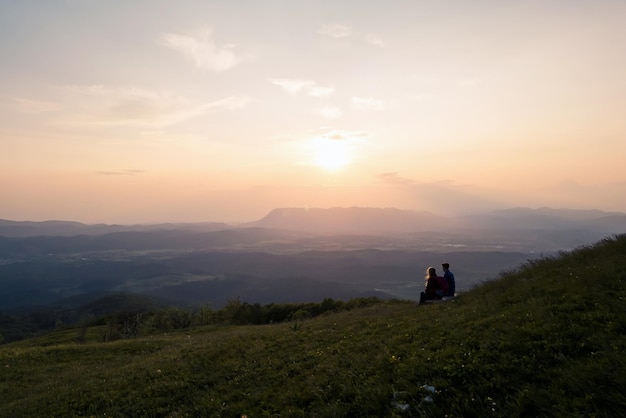 Um jovem casal desfrutando do fantástico panorama da montanha ao pôr-do-sol