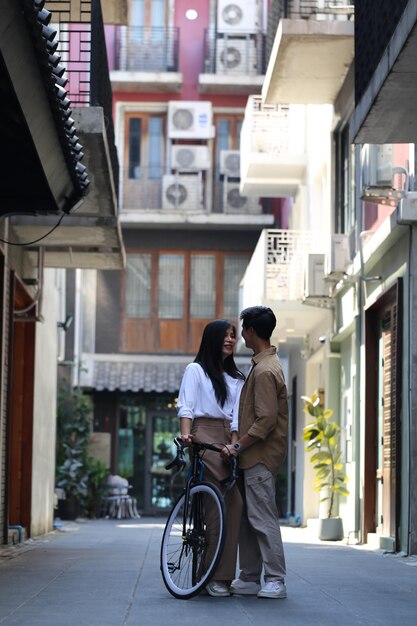 Um jovem casal e uma mulher asiática caminham juntos de bicicleta.