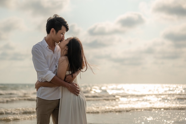 Um jovem casal em pé se beijando na praia ao pôr do sol da noite. Verão apaixonado. Dia dos namorados