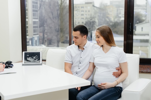 Foto um jovem casal em uma consulta de ginecologista após uma ultrassonografia. gravidez e cuidados de saúde.