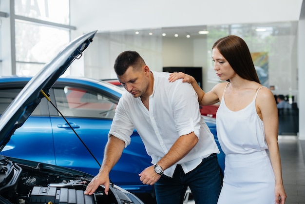 Um jovem casal escolhe um carro novo na concessionária e consulta um representante da concessionária.