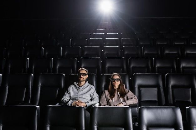 Um jovem casal está assistindo a um filme com óculos 3D em um elegante cinema Estreia do tão esperado filme