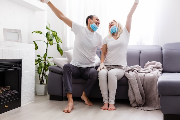 Um jovem casal está sentado em casa em quarentena. Marido e mulher colocaram o coronavírus em quarentena com máscaras protetoras. Nova realidade. Vida normal isolada. Leia um livro juntos. Itália europa covid-19