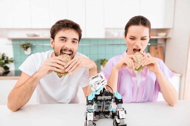 Um jovem casal está sentado na cozinha e comendo.