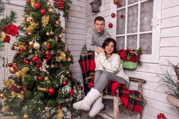 um jovem casal examina os presentes de Natal debaixo da árvore. homem e mulher se cumprimentam no