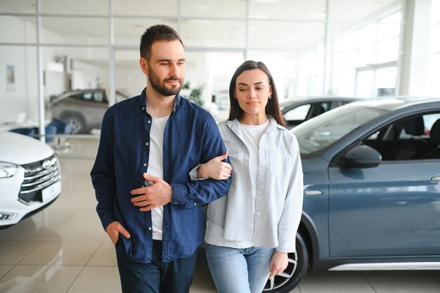 Um jovem casal feliz escolhe e compra um carro novo para a família Visitando a concessionária