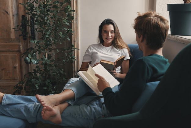 Um jovem casal feliz lendo livros enquanto se relaxa em casa juntos