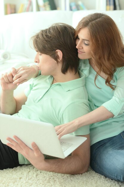 Um jovem casal feliz olhando para o laptop enquanto está deitado no chão