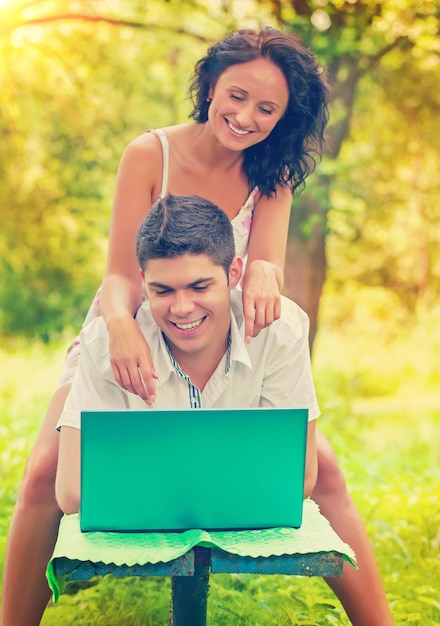 Um jovem casal feliz sorridente com laptop na cor do instagram do parque
