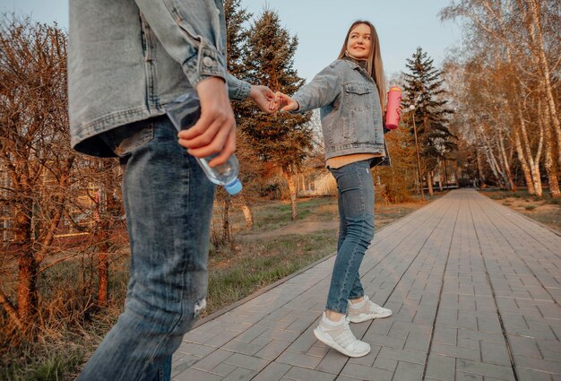 Um jovem casal gosta de uma caminhada refrescante no parque com garrafas de água, desfrutando de hidratação e serenidade.