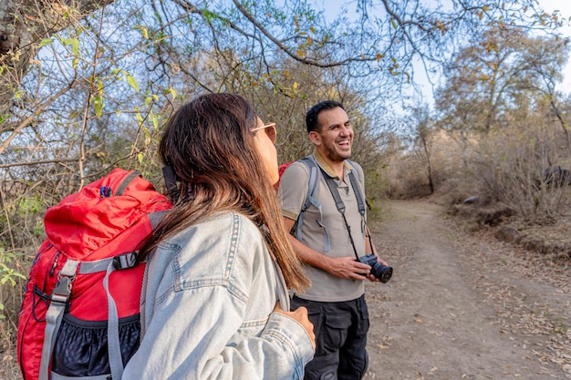 Foto um jovem casal latino a fazer uma caminhada no campo. pessoas felizes a viajar na natureza.