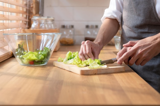 Um jovem casal LGBT entra na cozinha para fazer uma salada de frutas e vegetais para o jantar