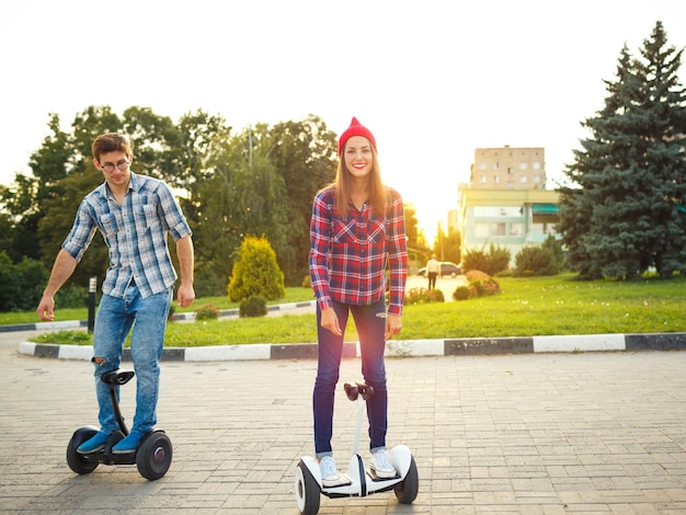 Foto um jovem casal montando hoverboard scooter elétrico pessoal eco transporte gyro scooter roda de equilíbrio inteligente