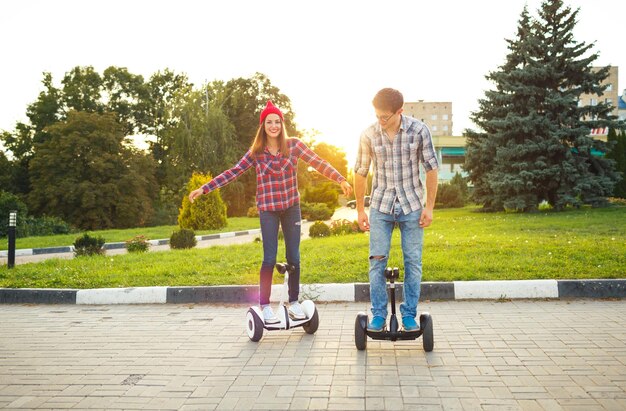 Foto um jovem casal montando um hoverboard scooter elétrico pessoal de transporte ecológico scooter giroscópico roda de equilíbrio inteligente