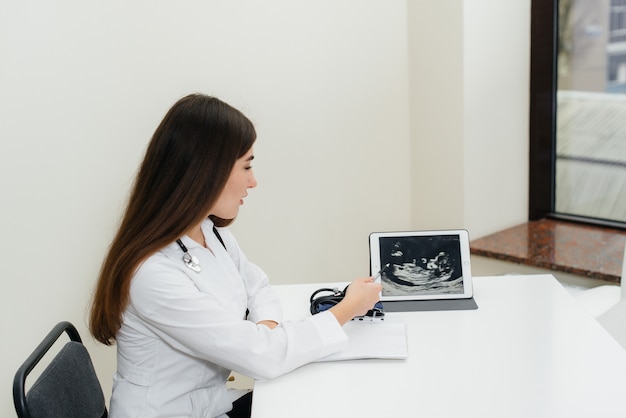 Um jovem casal na consulta de um ginecologista após um ultra-som. Gravidez e cuidados de saúde