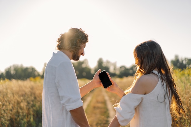 Um jovem casal na natureza olha para o telefone.