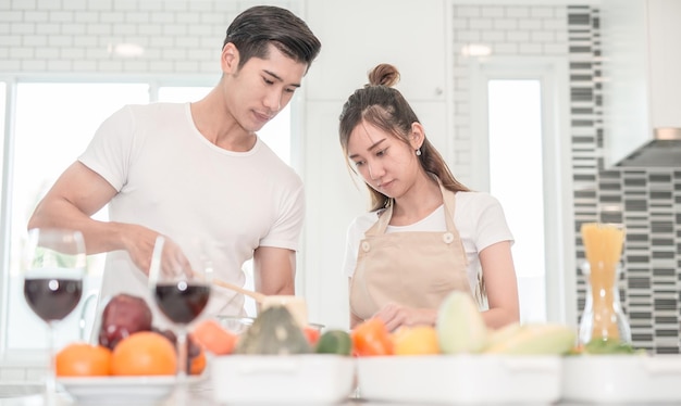 Um jovem casal preparando comida na cozinha em casa