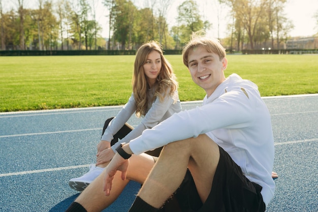 Um jovem casal se comunica e descansa no estádio após um bom treino no estádio Atletas de atletismo esportivo