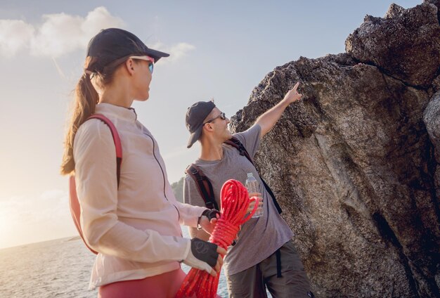 Foto um jovem casal sobe com uma corda até o topo das montanhas perto do oceano