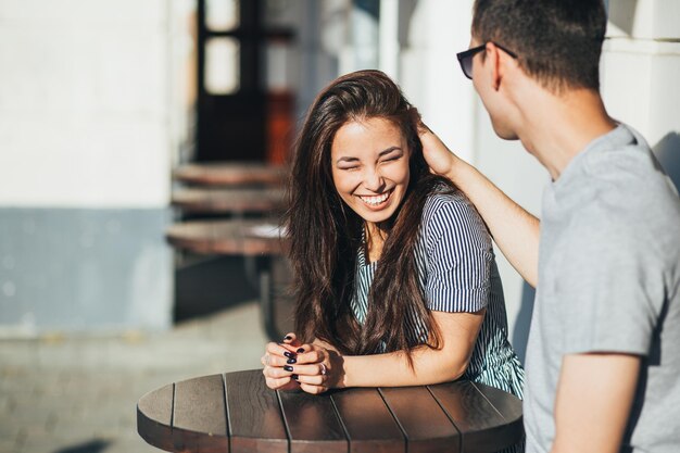 Foto um jovem casal sorridente sentado num café.