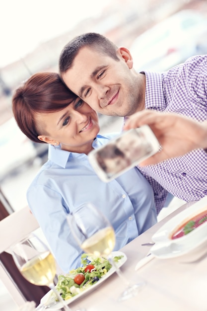 Um jovem casal tirando uma foto em um restaurante