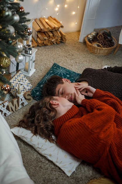 Foto um jovem casal tradicional feliz celebra o natal perto de uma bela árvore de natal