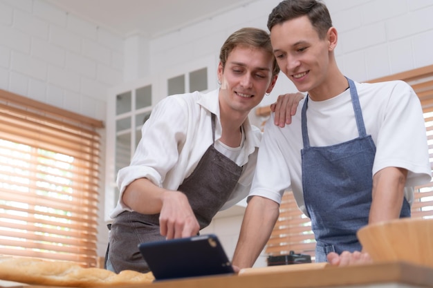 Um jovem casal vai para a cozinha e aprende a fazer biscoitos online.