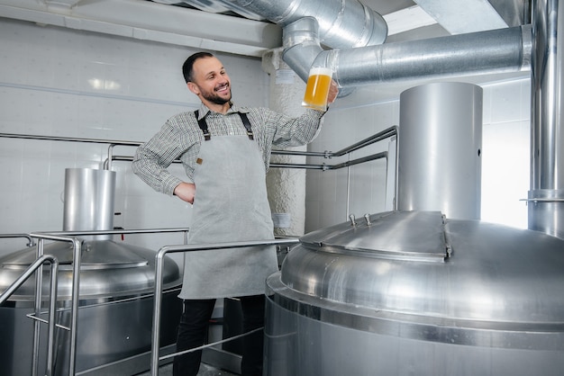 Um jovem cervejeiro barbudo conduz o controle de qualidade da cerveja acabada de fazer na cervejaria.