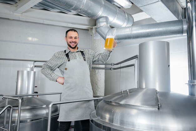 Um jovem cervejeiro barbudo conduz o controle de qualidade da cerveja acabada de fazer na cervejaria.