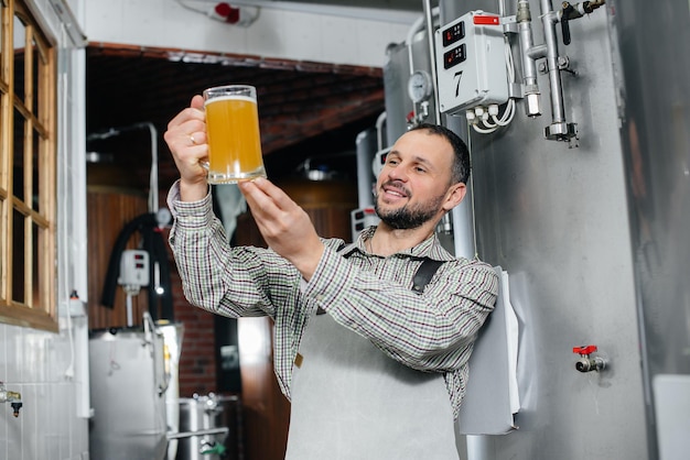 Foto um jovem cervejeiro barbudo conduz o controle de qualidade da cerveja acabada de fazer na cervejaria.