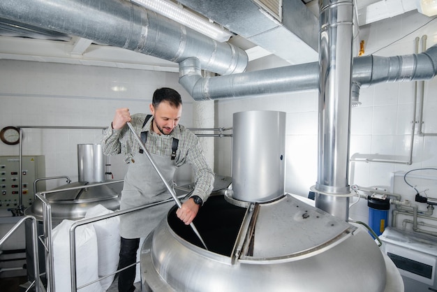 Um jovem cervejeiro está envolvido no processo de fabricação de cerveja em uma pequena cervejaria. Produção de cerveja.