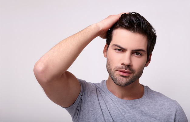 Foto um jovem charmoso e forte segura a mão pelo cabelo.