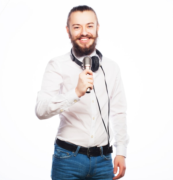 Foto um jovem com barba vestindo uma camisa branca segurando um microfone