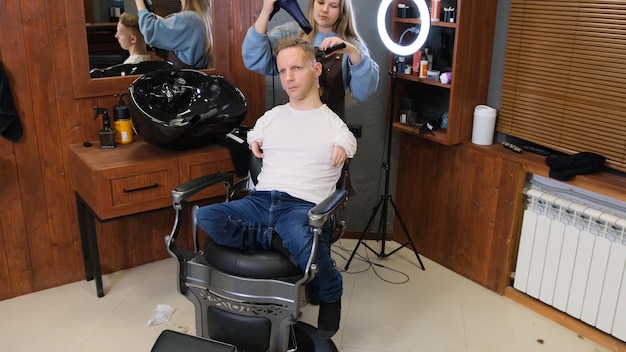 Um jovem com patologia de deficiência da área da mão corta o cabelo em uma barbearia