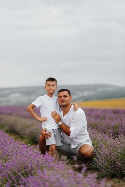 Um jovem com seu filho está caminhando por um belo campo de lavanda e apreciando a fragrância das flores. Descanse e bela natureza. Unidade com a natureza e harmonia.