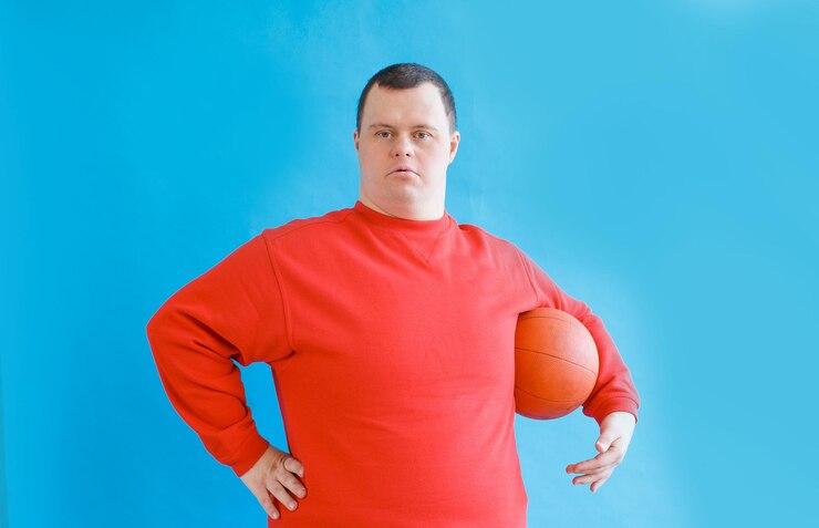 Foto um jovem com síndrome de down sorri com uma bola de beisebol nas mãos sobre um fundo azul isolado