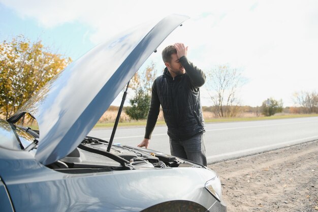 Foto um jovem com um carro preto que quebrou no espaço roadcopy